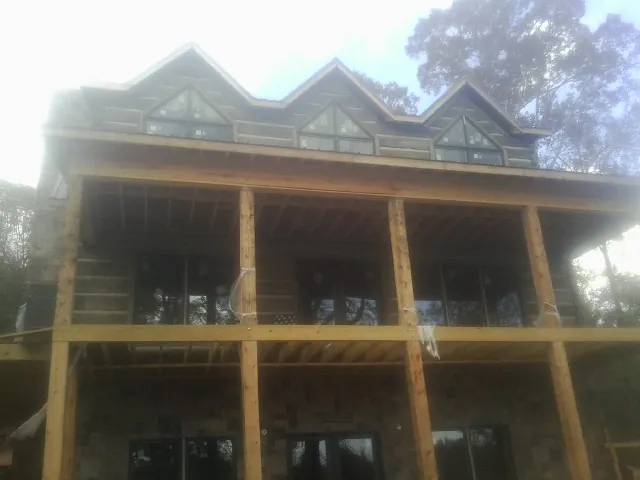 Dormers and porch framing on a large log home under construction — Roof Coating work by our crew in Center Rutland
