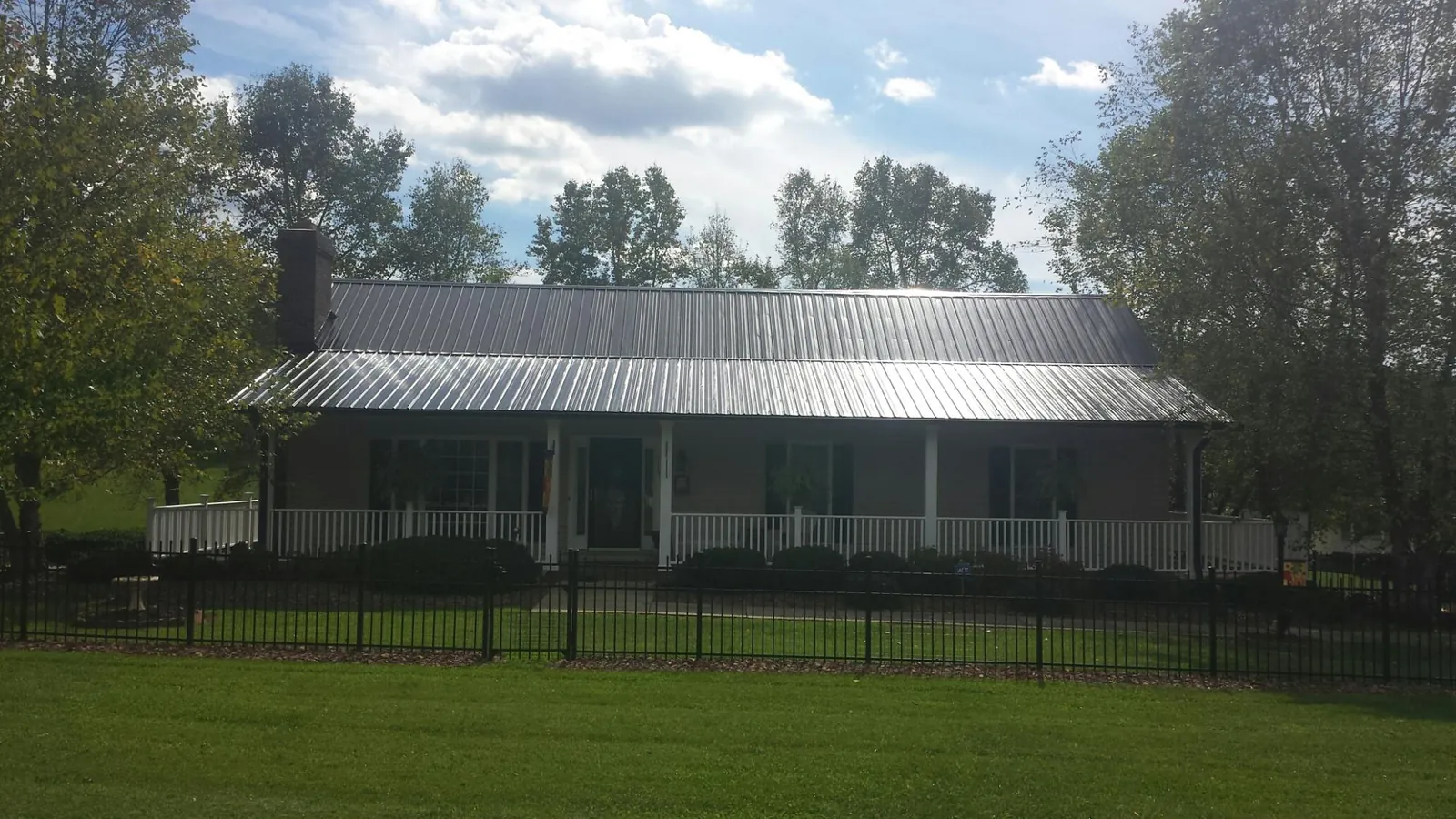 Gray metal roof on a brick ranch with a full width front porch — Gutter Guard Installation work by our crew in Center Rutland
