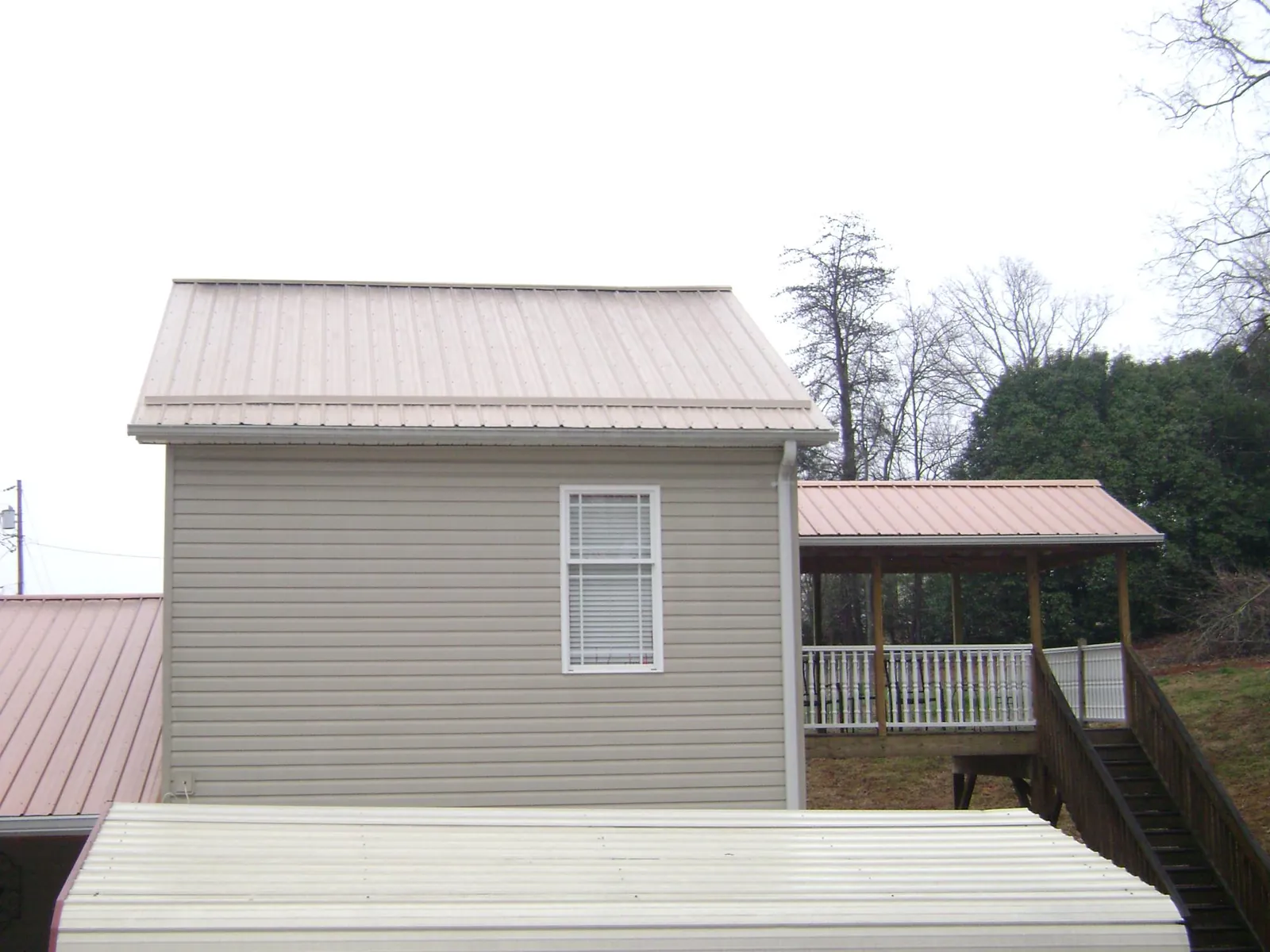 Tan metal roofs on a two story addition and attached porch, from a Roof Replacement job in Center Rutland