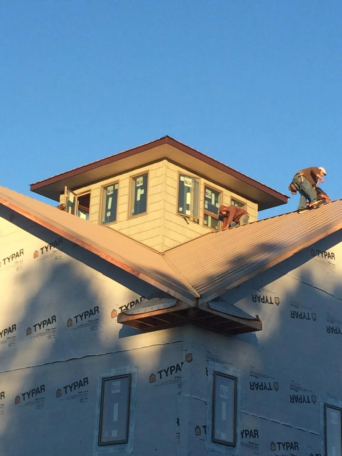 Roofers working around a rooftop cupola on a new metal roof at sunset — Roof Waterproofing in Center Rutland by Roofing Brothers